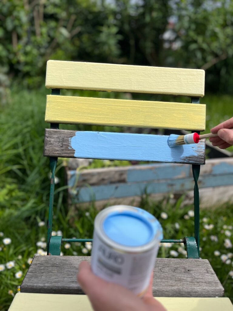 Dose mit blauem Lack von AURO vor einem Gartenstuhl