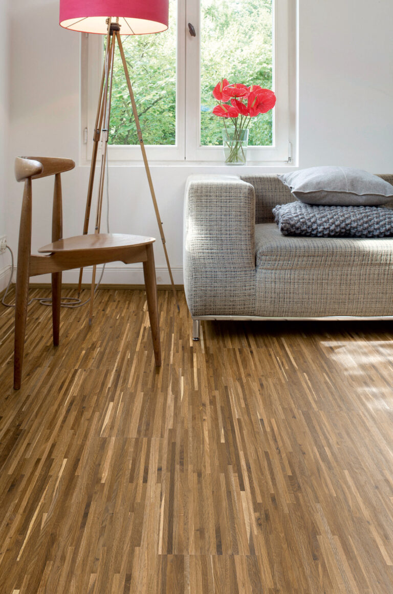 helles Wohnzimmer mit Boden in Stäbchenoptik, graues Sofa, Holzstuhl, pinke Lampe
