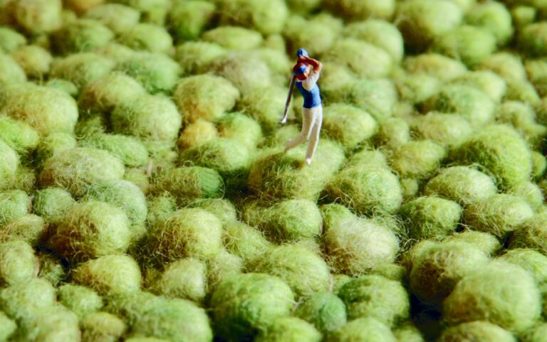 Nahaufnahme grüner Wollteppich mit Mini-Figur eines Golfers