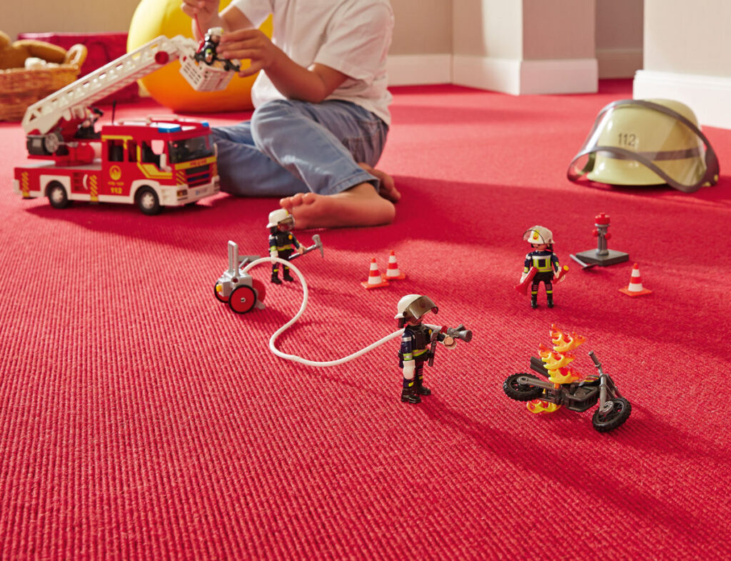 tretford Teppich aus Kaschmir-Ziegenhaar und Schurwolle roter Teppich auf dem Kind mit Playmobil-Feuerwehr spielt