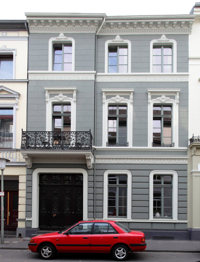 graue Altbaufassade mit Stuckverzierung