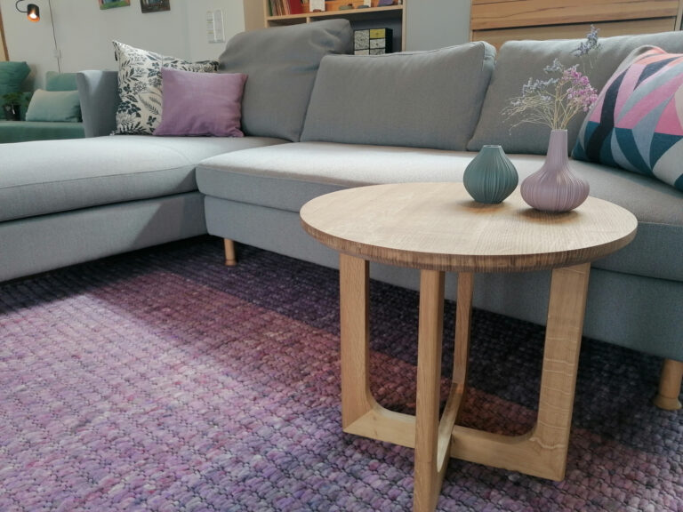 Nahansicht eines grauen Sofas, vor dem ein kleiner, runder Couchtisch steht
