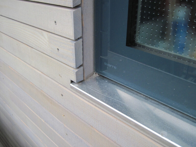 Detailansicht Fassade mit Holzverkleidung und grauem Fenster