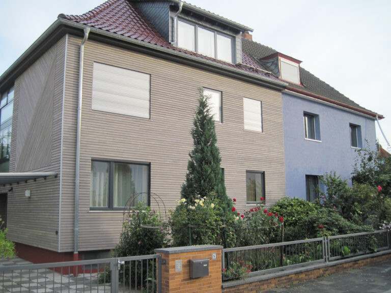 frisch renoviertes Doppelhaus, links mit Holzverkleidung, rechts blau verputzt