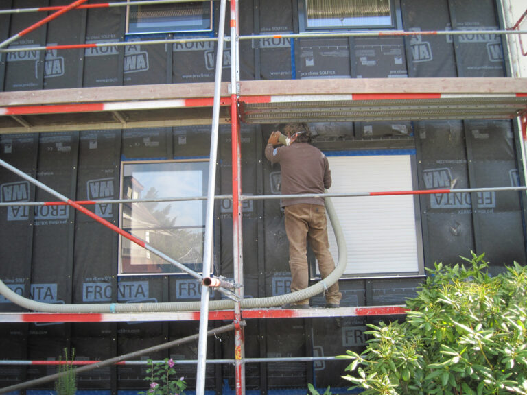 Fassade mit Gerüst, auf dem ein Arbeiter steht