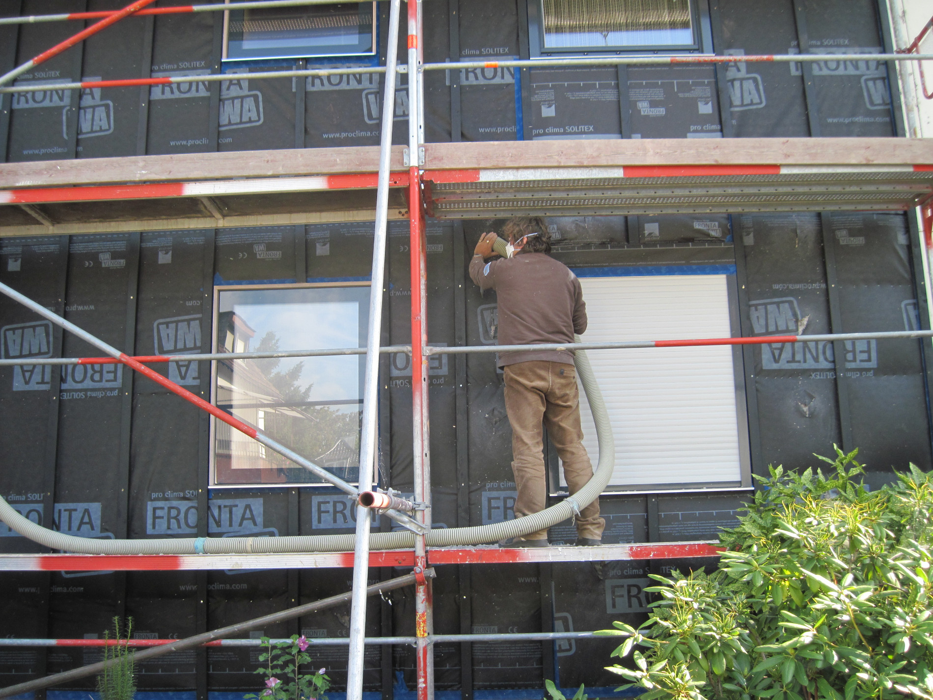 Fassade mit Gerüst, auf dem ein Arbeiter steht