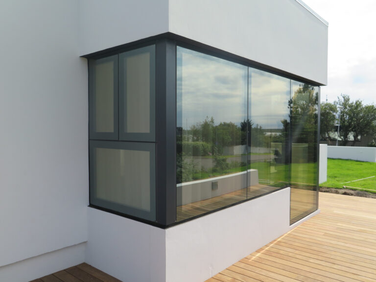 weißer Flachbau mit Holzterrasse, mit flächenbündigen Fenstern
