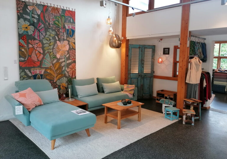 Ausstellung in einem Geschäft mit blauem Sofa und Wandteppich