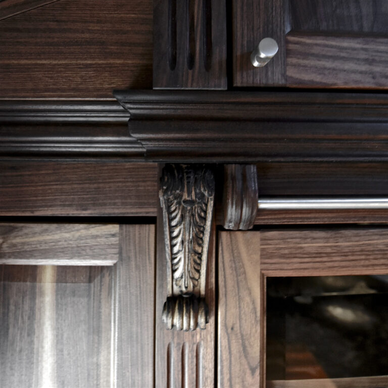 Kapitell an einem Schrank aus dunklem Holz