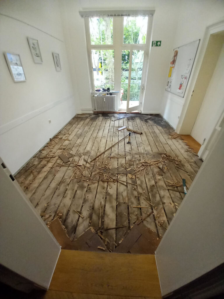 leerer Raum, in dem noch Reste eines alten Fischgratparkett zu sehen sind