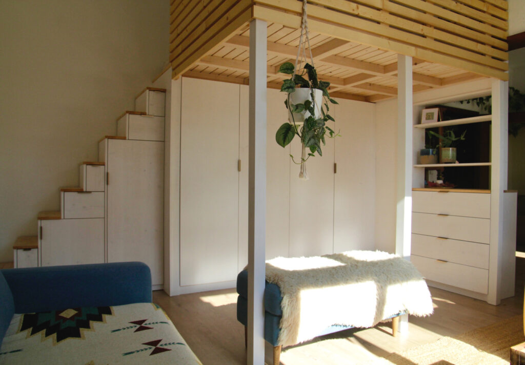 Das Hochbett kombiniert Schlafen und Wohnen mit maximalem Stauraum. Hochbett in hellem Holz, unter dem weiße Einbaumöbel eingepasst wurden