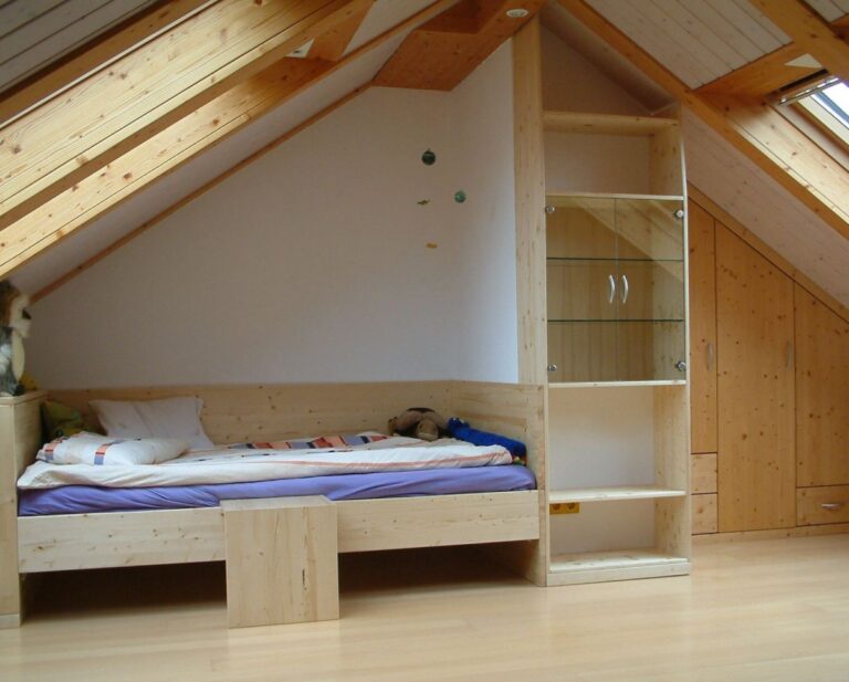 Zimmer mit in Dachschräge eingebauten Möbeln und Bett