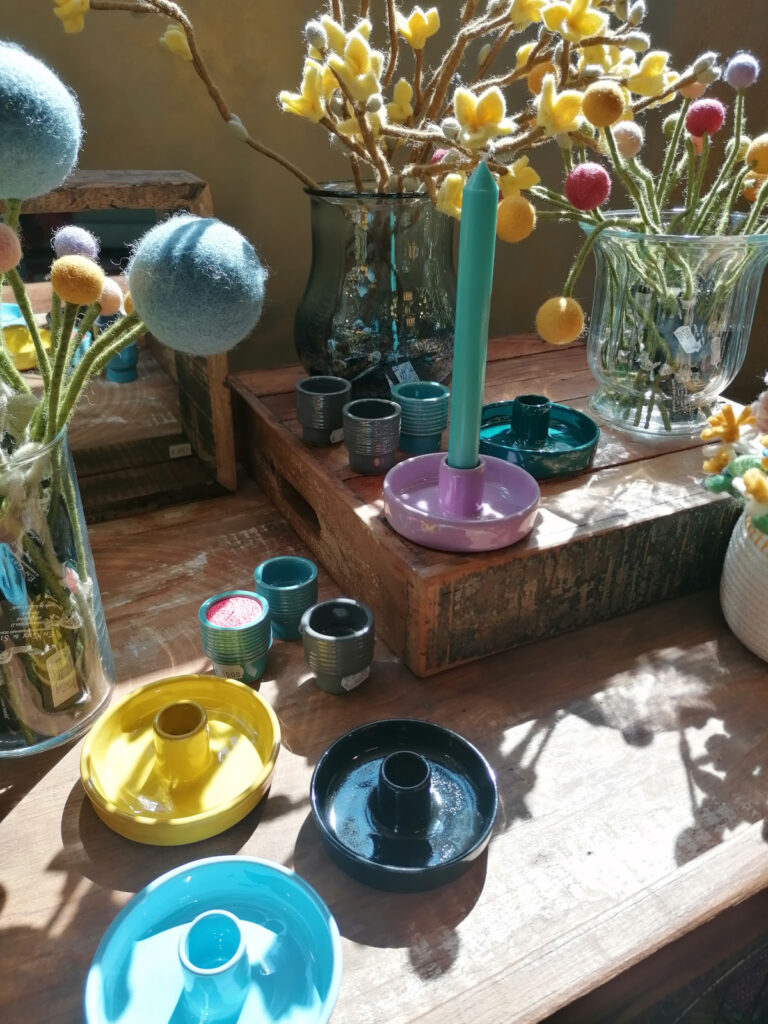 verschiedene bunte Kerzenständer und Filzblumen stehen auf einem Tisch aus rustikalem Altholz
