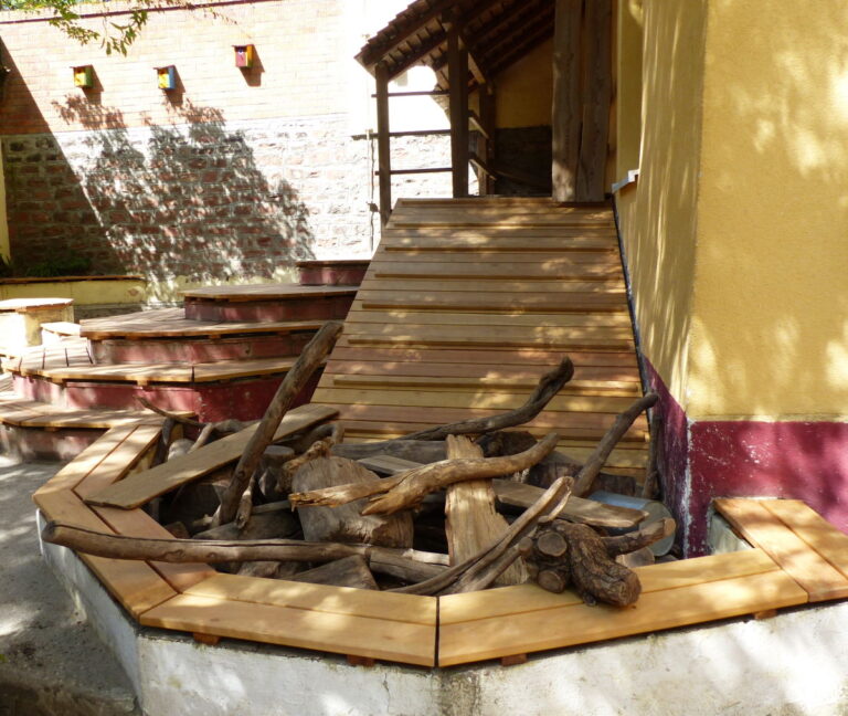 Außenbereich eines Kindergartens mit Sitzflächen aus Holz