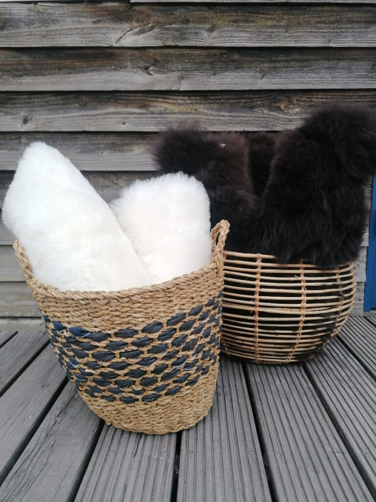 Körbe mit Schaffellen stehen draußen auf einer Holzterrasse