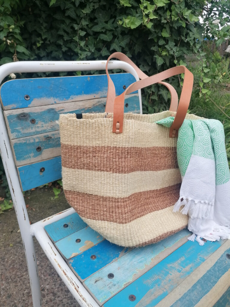 Korb von Mifuko, Altholz-Stuhl von Nature&Style naturfarbene Korbtasche steht auf einem blauen Gartenstuhl