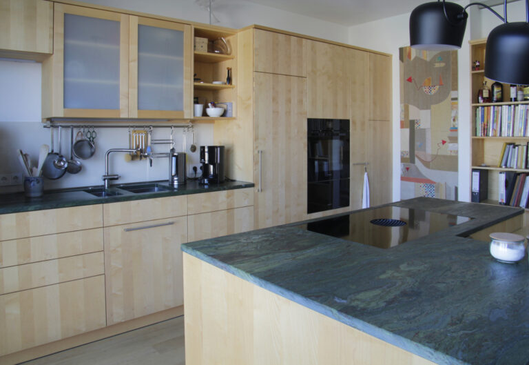 helle Holzküche mit bunt-grüner Steinarbeitsplatte