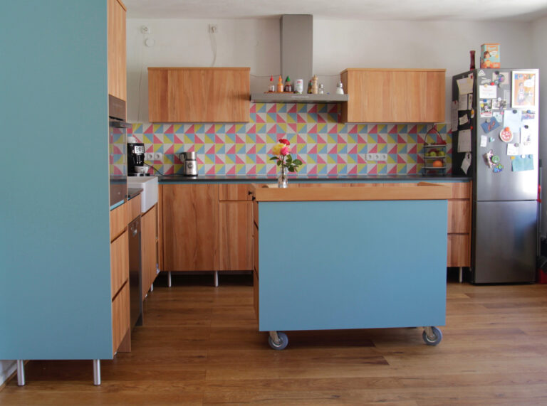 helle Holzküche mit blauen Fronten und buntem Fliesenspiegel