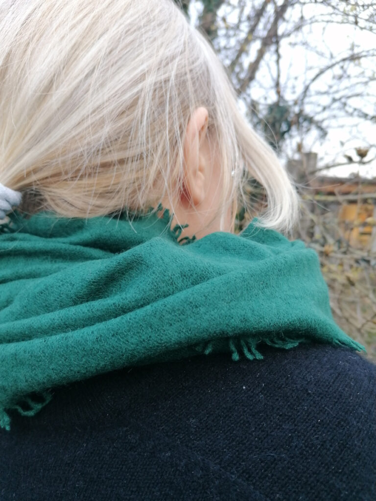 Frau mit blonden Haaren trägt einen grünen Schal