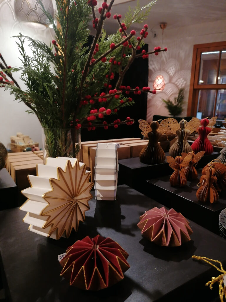 schwarzer Tisch, auf dem Weihnachtsornamente aus Papier präsentiert sind