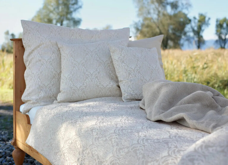 Bett auf einem Feldweg mit cremefarbener Bettdecke und Kissen mit Paisleymuster