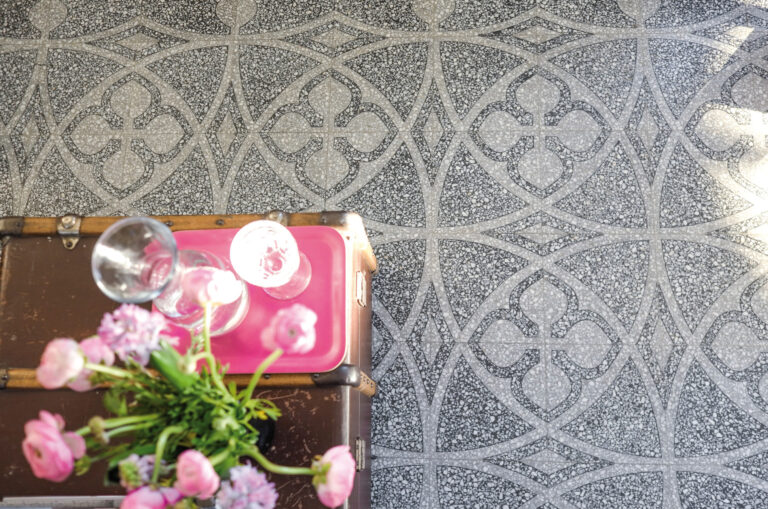 Terrazzofliesen auf denen ein alter Koffer und rosa Anemonen stehen