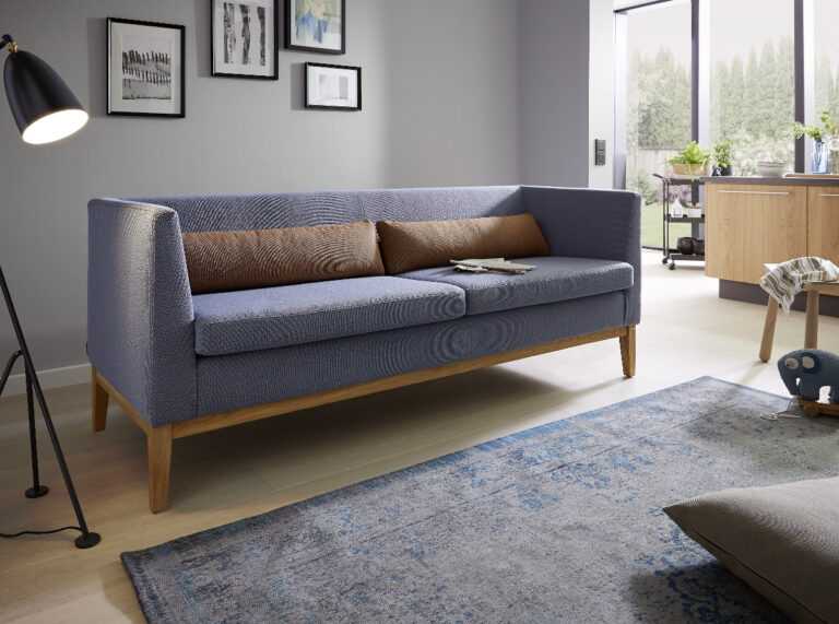 blaues, niedriges Dining-Sofa mit braunen Kissen und Holzsockel
