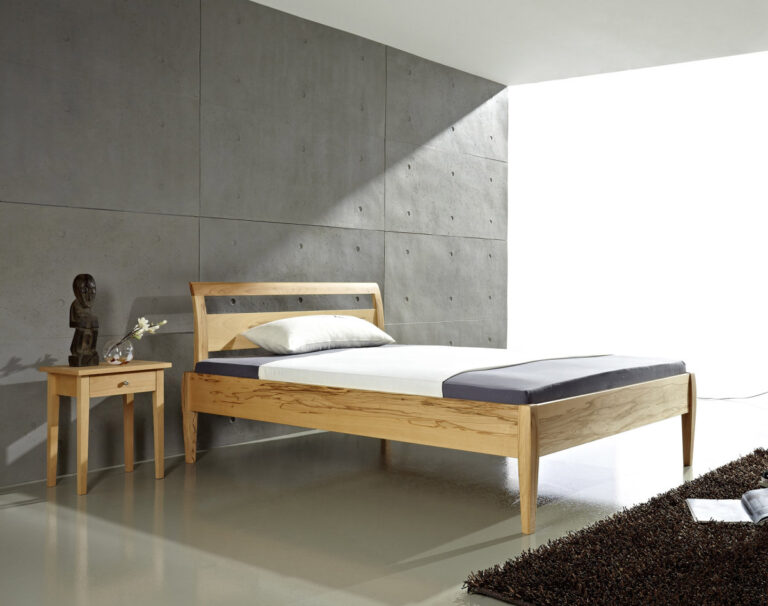 Bett aus hellem Holz mit geschwungenen Füßen und passendem Nachttisch
