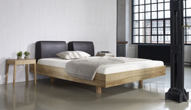 Holzbett mit Kopfpolstern aus Leder in einer Industriehalle