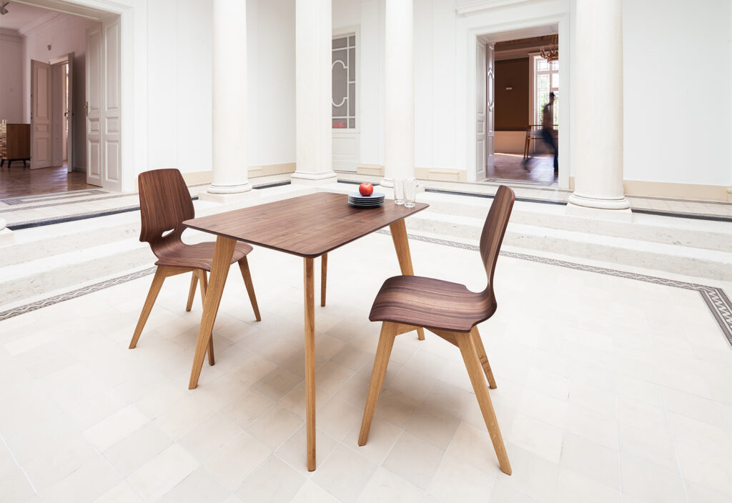 sixay: Stuhl und Tisch FINN 2 Stühle an einem kleinen Tisch aus dunklem Holz in einer musealen Halle