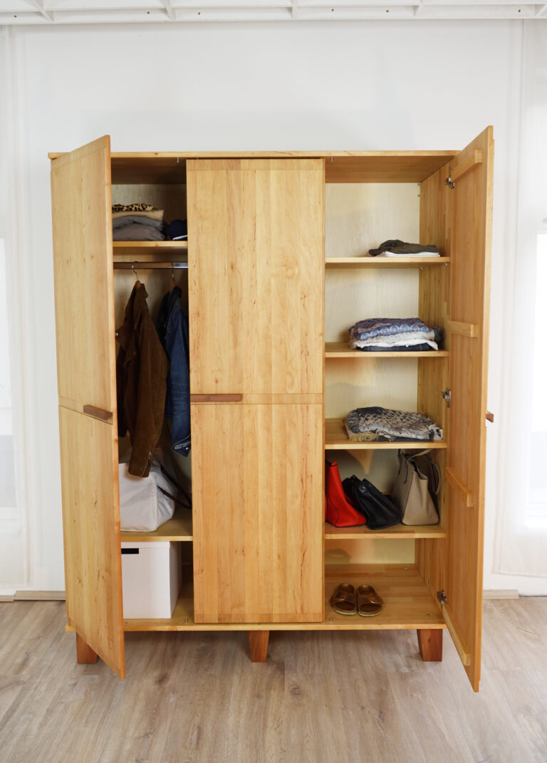 Kleiderschrank aus hellem Holz mit zwei geöffneten und einer offenen Tür