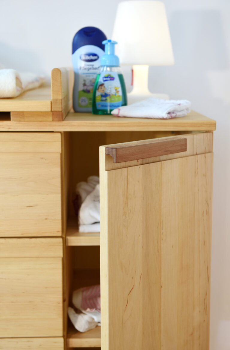 offene Tür an einer Wickelkommode aus hellem Holz
