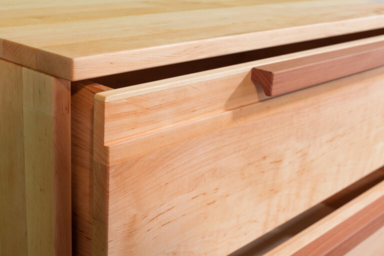 Detailansicht der Schublade einer Kommode aus hellem Holz