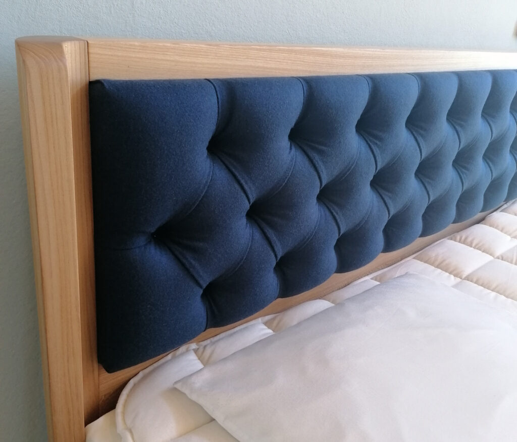 Kopfteil eines Holzbettes mit blauem Wollfilz