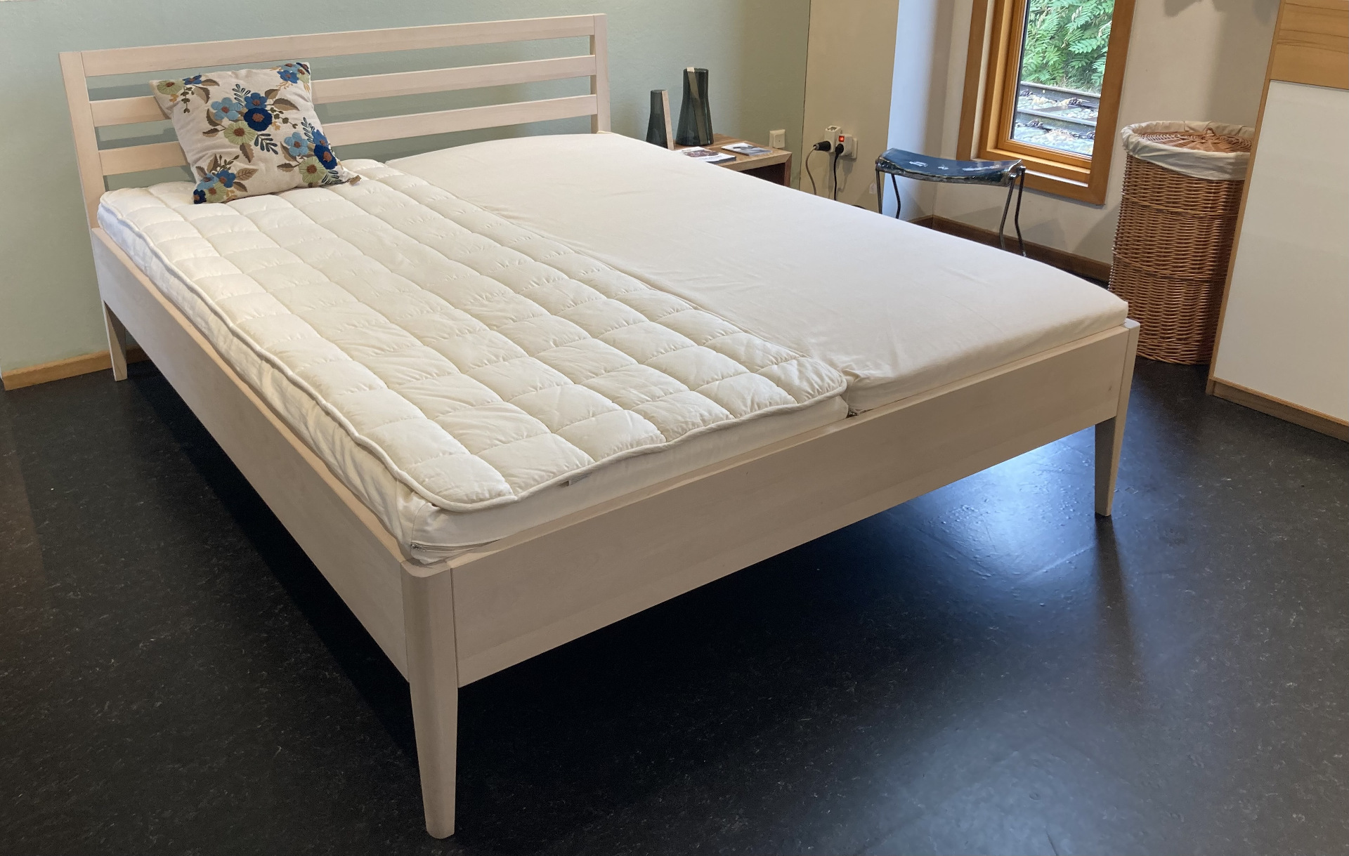 Bett aus hellem Holz mit einem Blümchenkissen